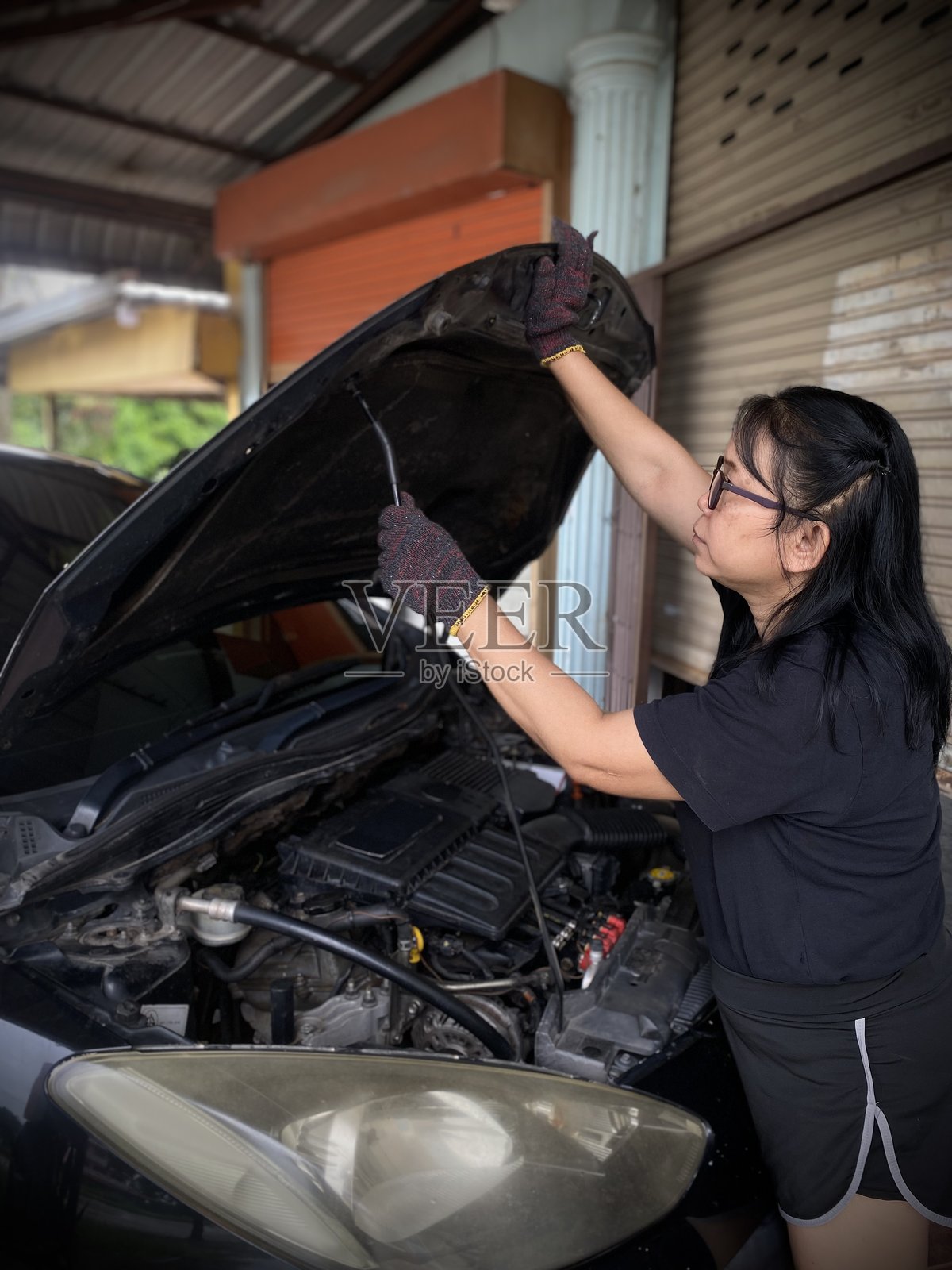 将引擎盖完全抬起，并用支撑杆将其撑住。照片摄影图片