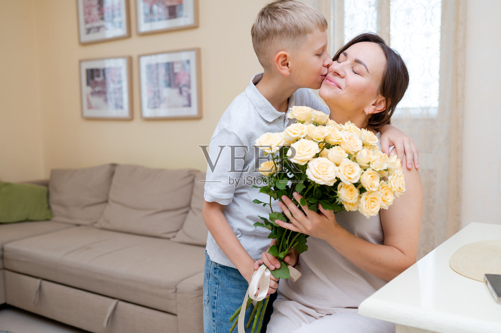 青少年男孩在母亲节送上黄色玫瑰花束，拥抱并亲吻母亲照片摄影图片