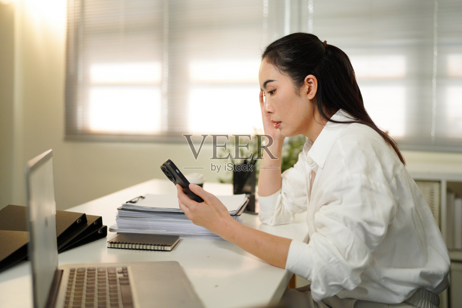 一位年长的职业女性在工作中因疲劳而担忧，头痛欲裂。这位40多岁、心烦意乱的职业女性感到压力重重，面临工作难题，在办公室盯着笔记本电脑。照片摄影图片