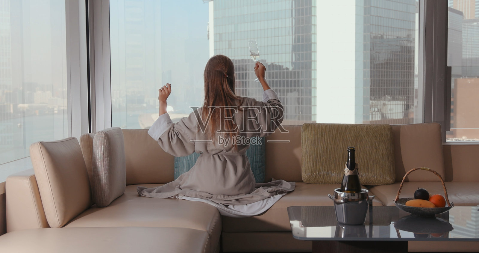 身着浴袍的女子坐在豪华酒店的沙发上，欣赏着城市美景，享受着悠闲时光照片摄影图片