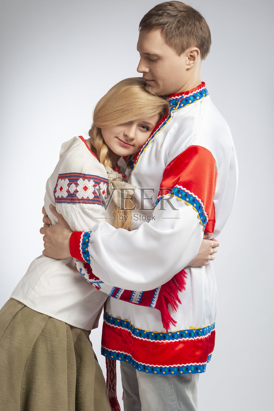 家庭概念。一对相爱的白种人夫妇身着装饰精美的白俄罗斯和俄罗斯民族刺绣服装，拥抱在一起，背景为白色。照片摄影图片