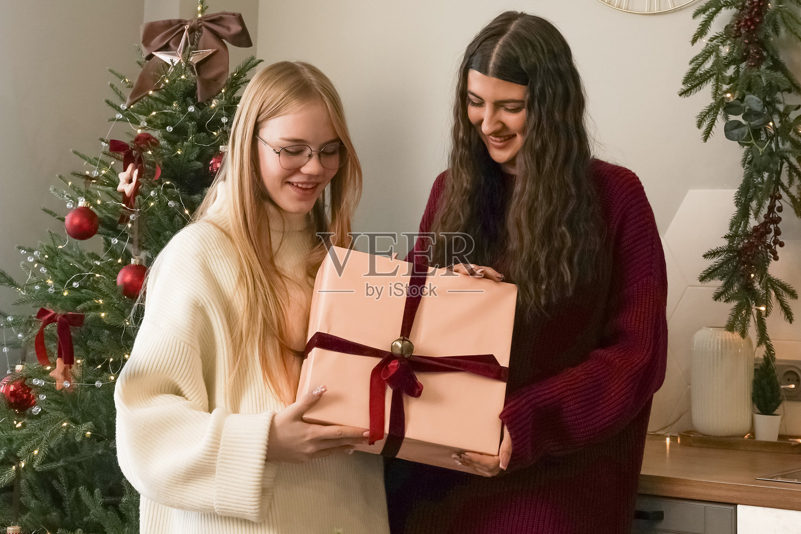 在节日期间，朋友们在一个舒适、装饰过的客厅里交换礼物照片摄影图片