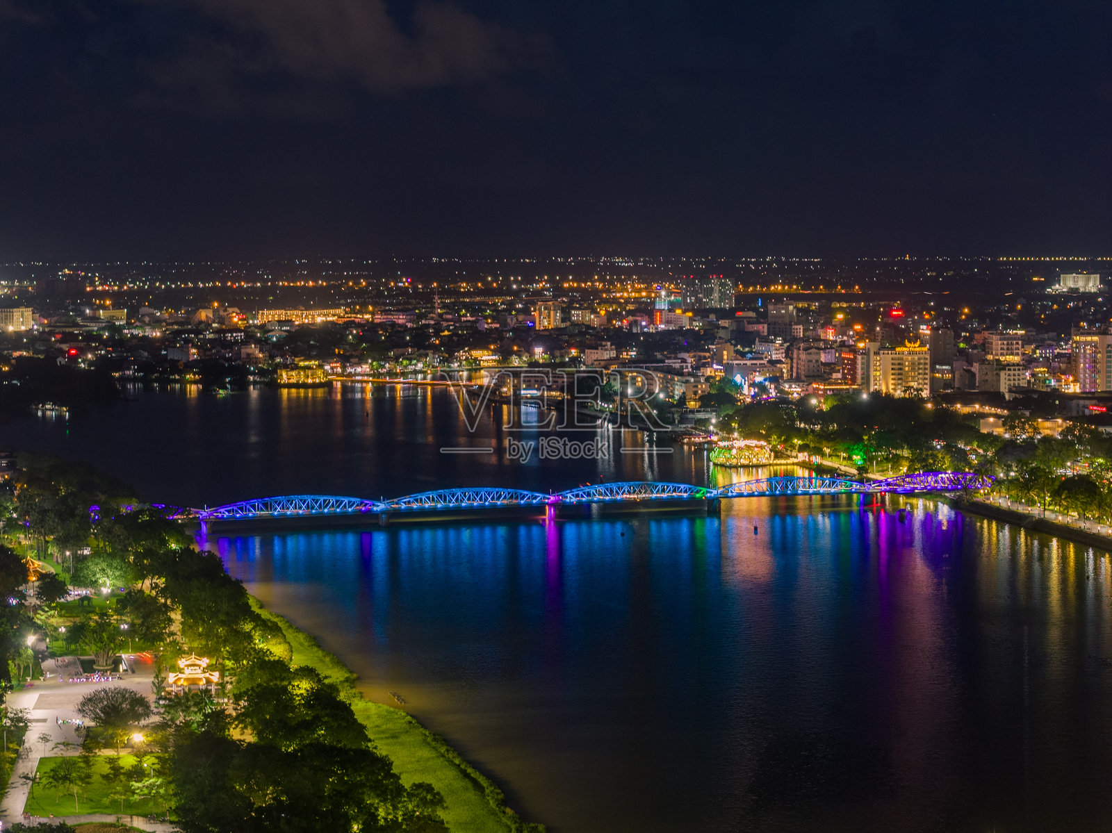 夜幕下顺化市香江桥的全景。桥梁通体被照亮，在水面上留下模糊的倒影。照片摄影图片