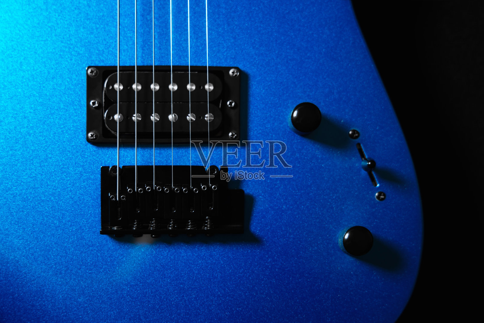 黑色背景上的蓝色电吉他，特写琴弦、拾音器和琴桥，适用于摇滚和录音室设计的乐器概念。照片摄影图片