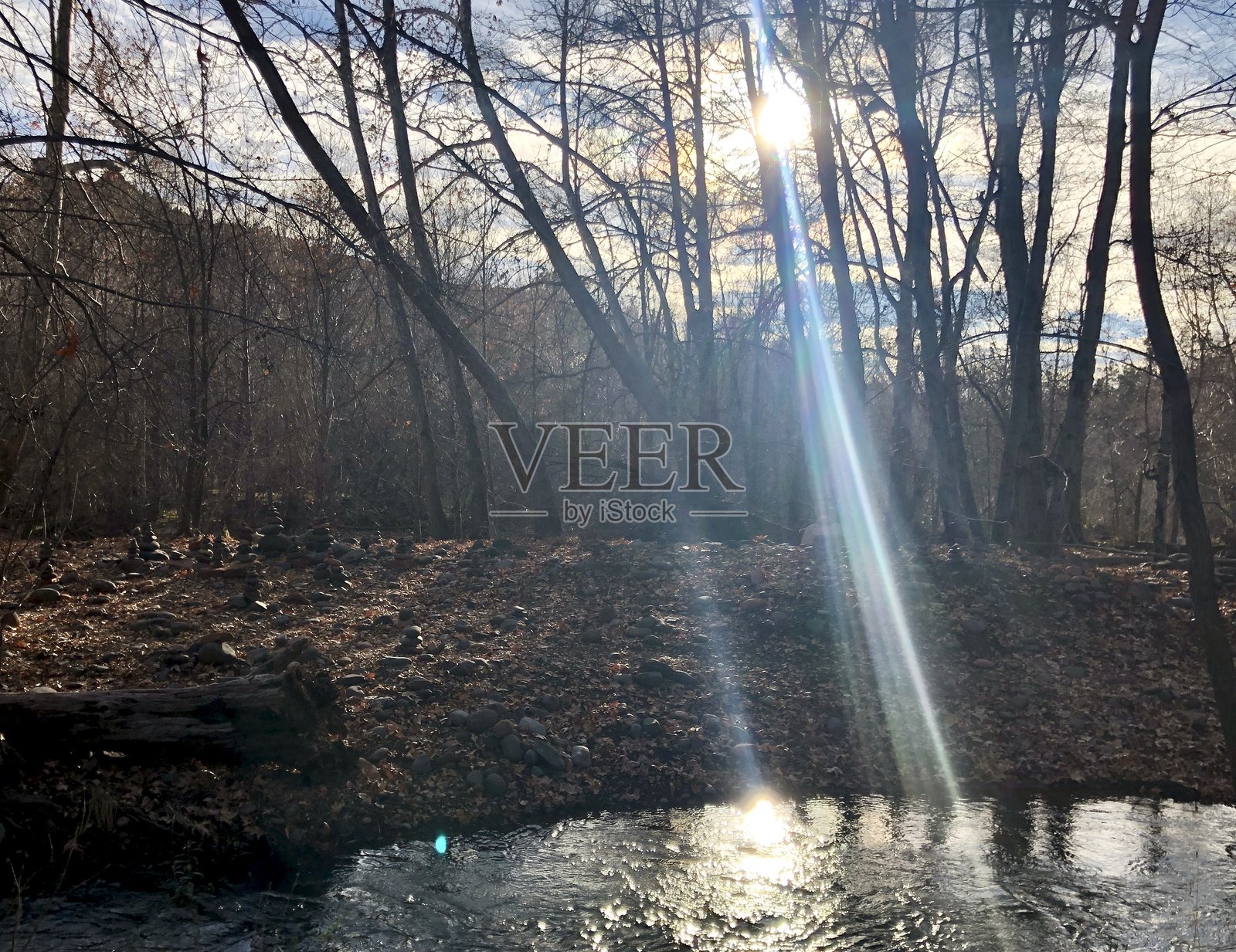 午后的阳光穿透云层和树林，岩石堆（石塔），河流潺潺，秋季照片摄影图片