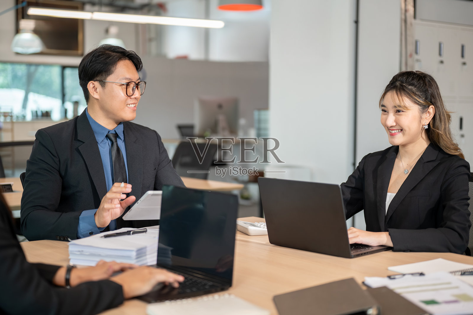 戴眼镜的商人与女同事在办公室的木桌旁开会交谈照片摄影图片