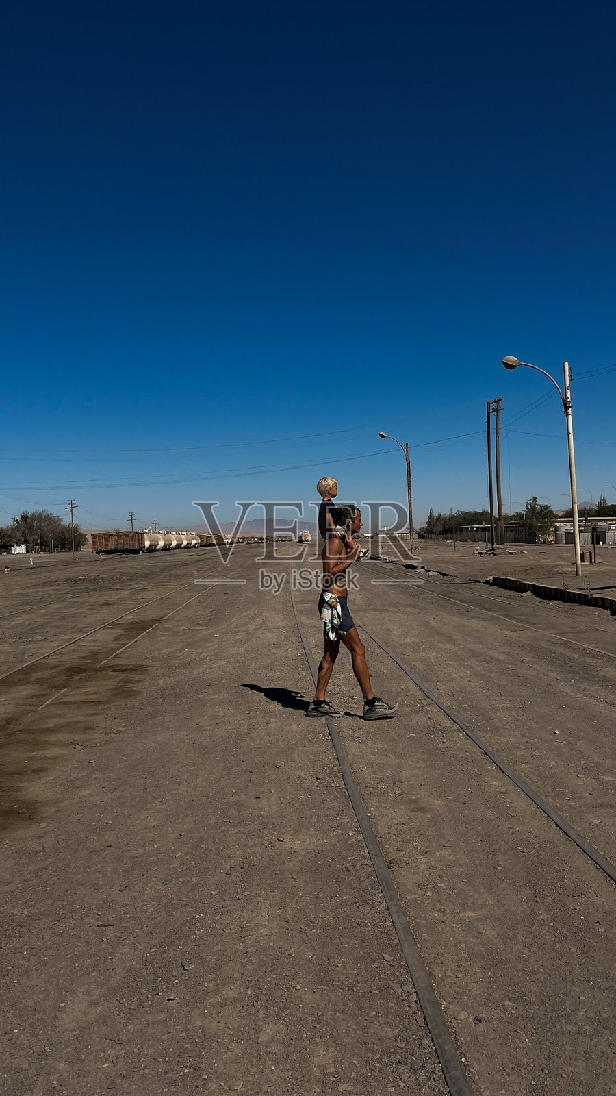 智利巴奎达诺火车站，一位运动型男子扛着他的小儿子，在古老的火车站上行走照片摄影图片