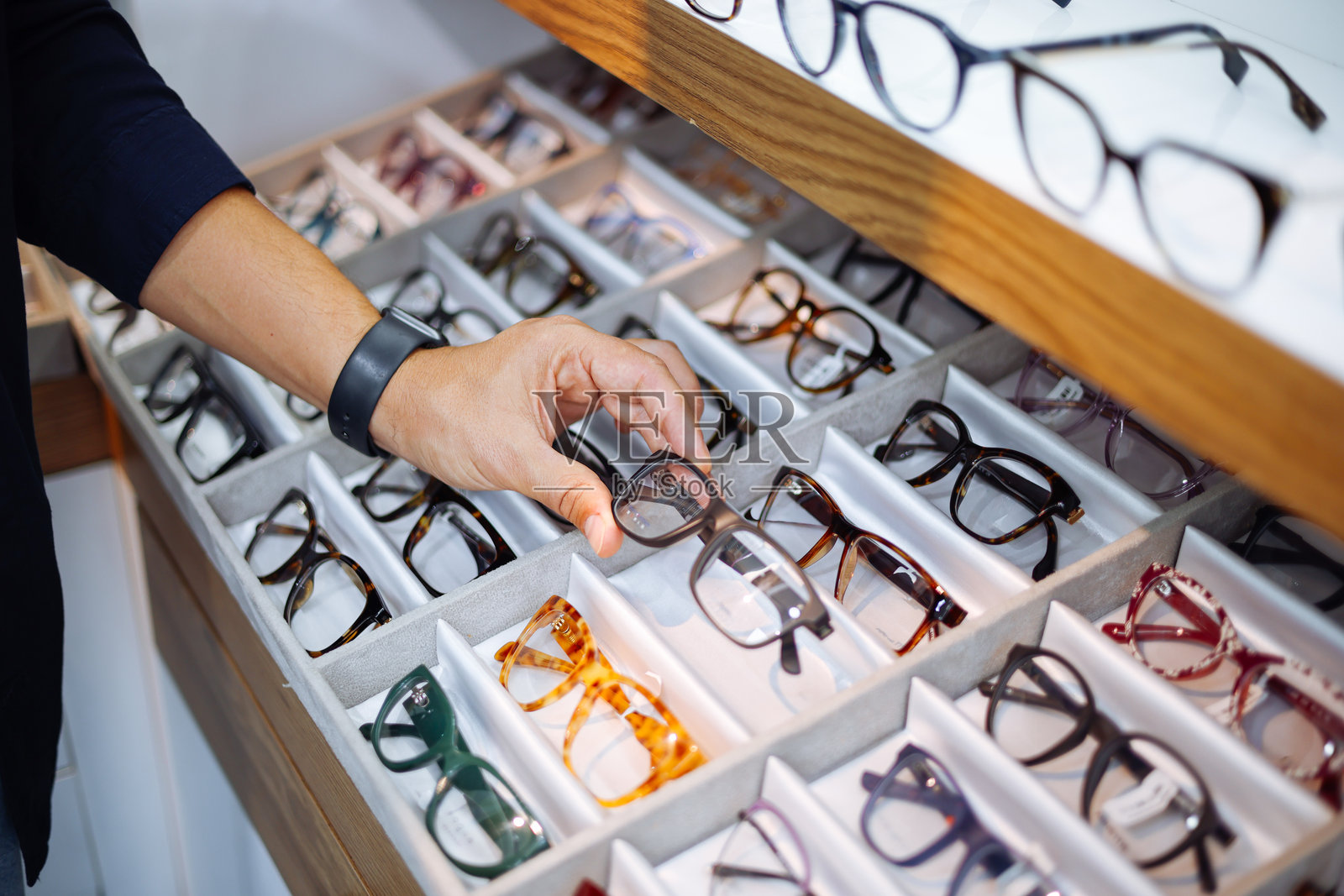 男士在眼镜店的货架上取下眼镜照片摄影图片