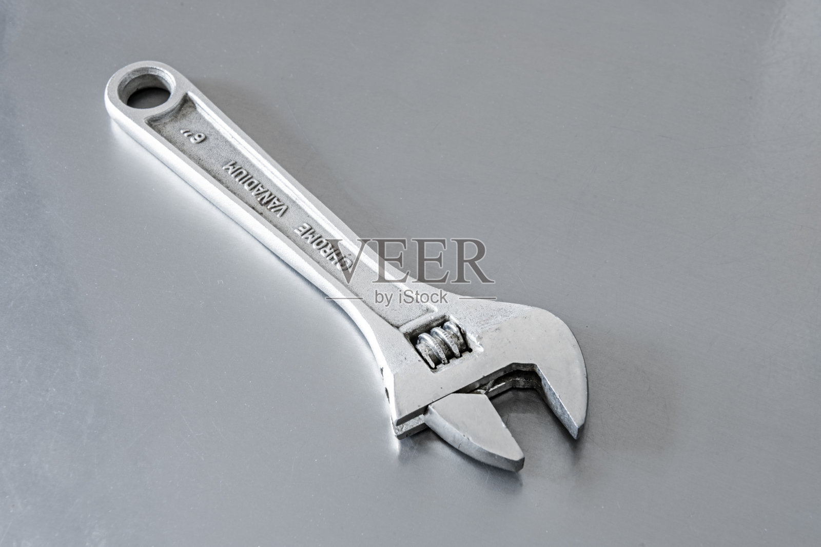 坚硬的钢扳手放在闪亮的灰色表面上照片摄影图片