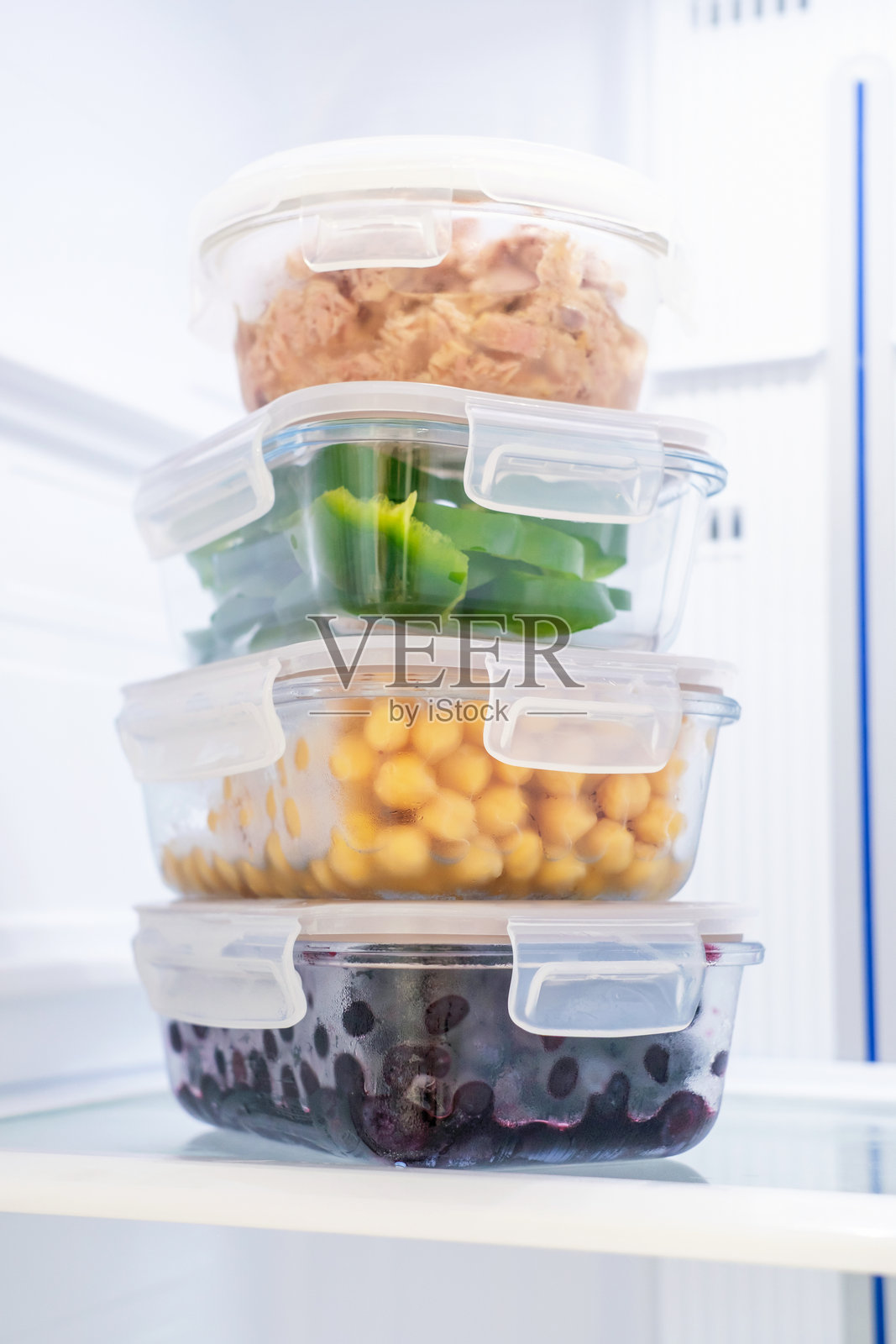 冰箱里的玻璃罐装浆果、蔬菜和金枪鱼，食物储存概念。照片摄影图片