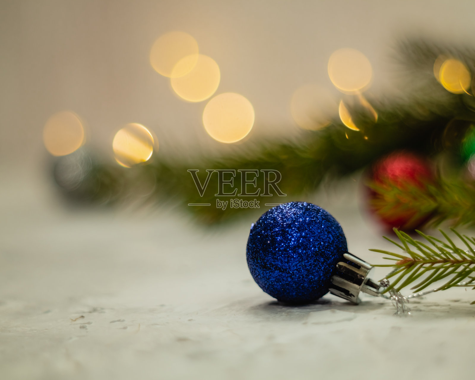 一个蓝色的圣诞装饰球挂在圣诞树上，背景是模糊的金色散景光。照片摄影图片