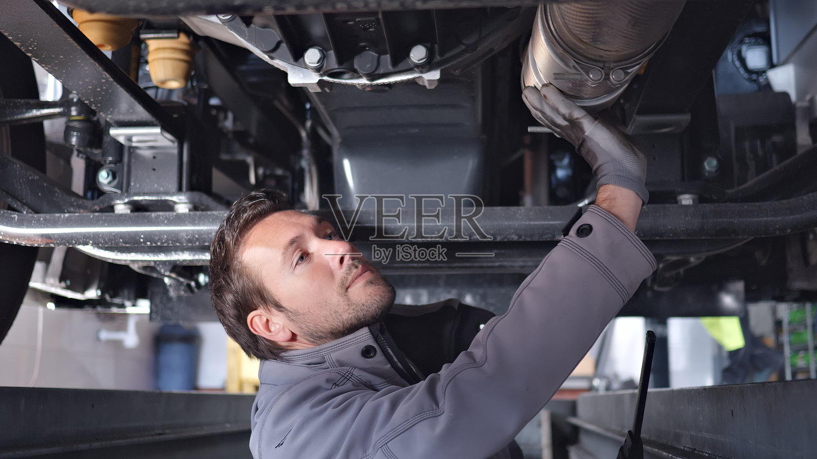 机械师在车辆下方检查发动机部件照片摄影图片