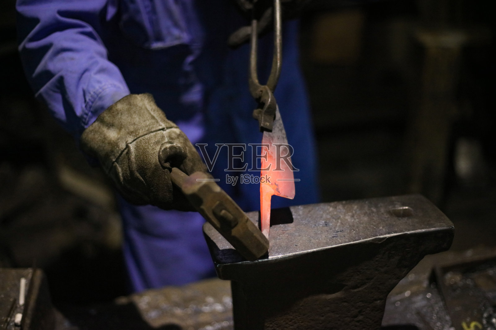 一位工匠正在将加热的材料锻打成形照片摄影图片