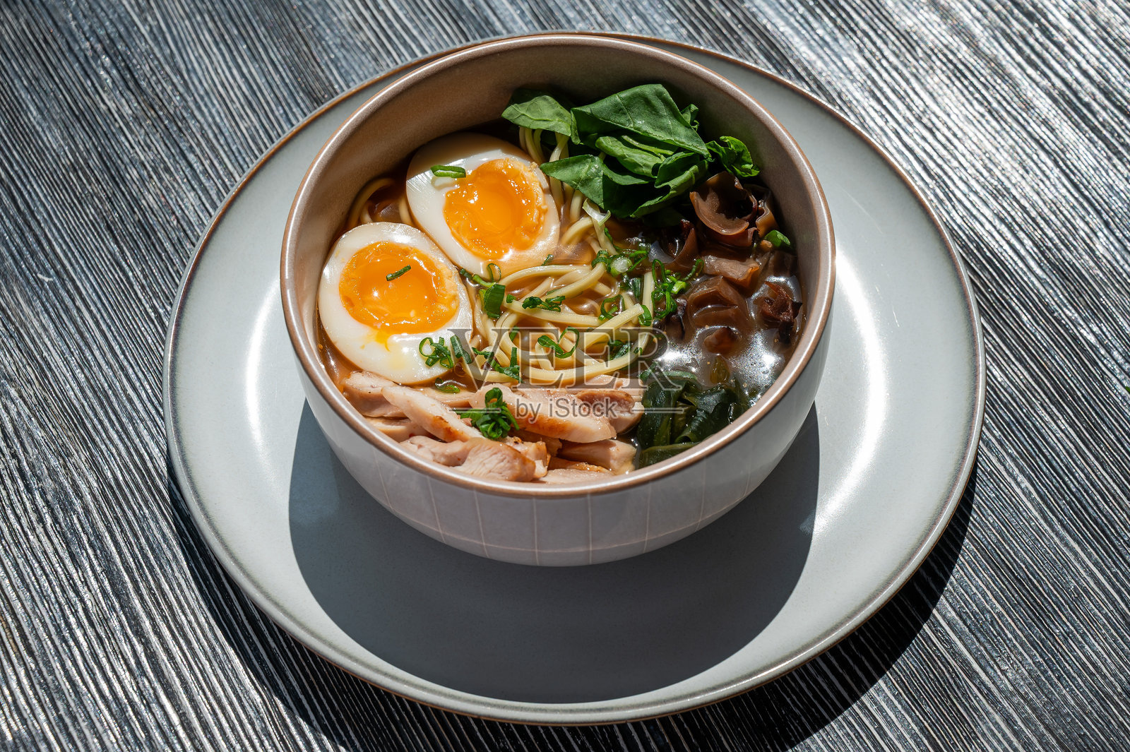 咖啡馆里木桌上的拉面汤。照片摄影图片