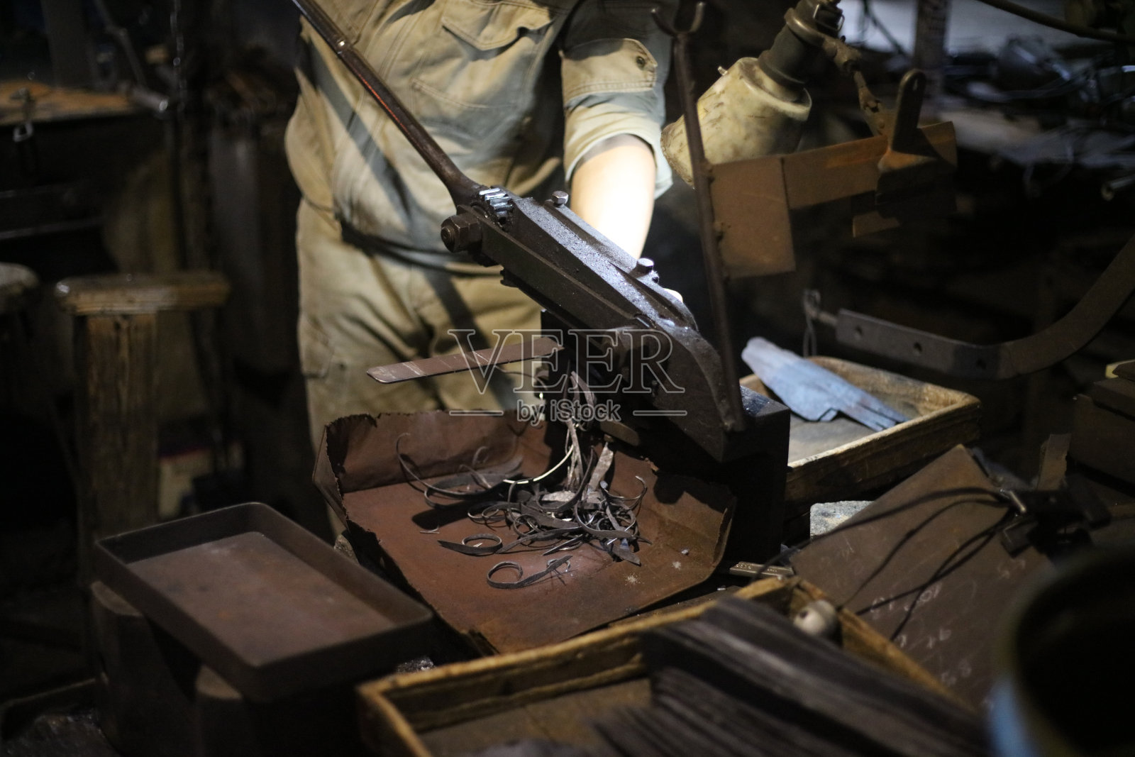 一位工匠用手动剪刀将材料剪成刀的形状照片摄影图片