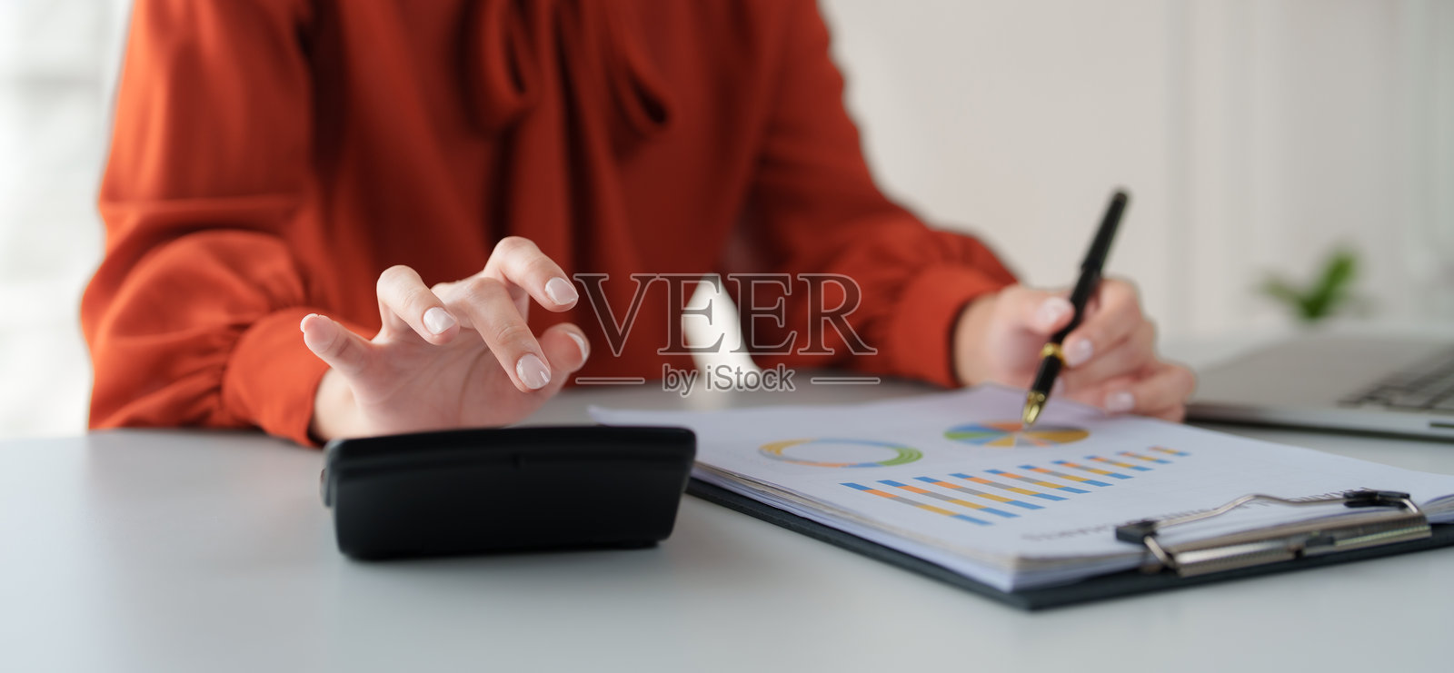 女商人正在办公室分析财务图表并使用计算器照片摄影图片