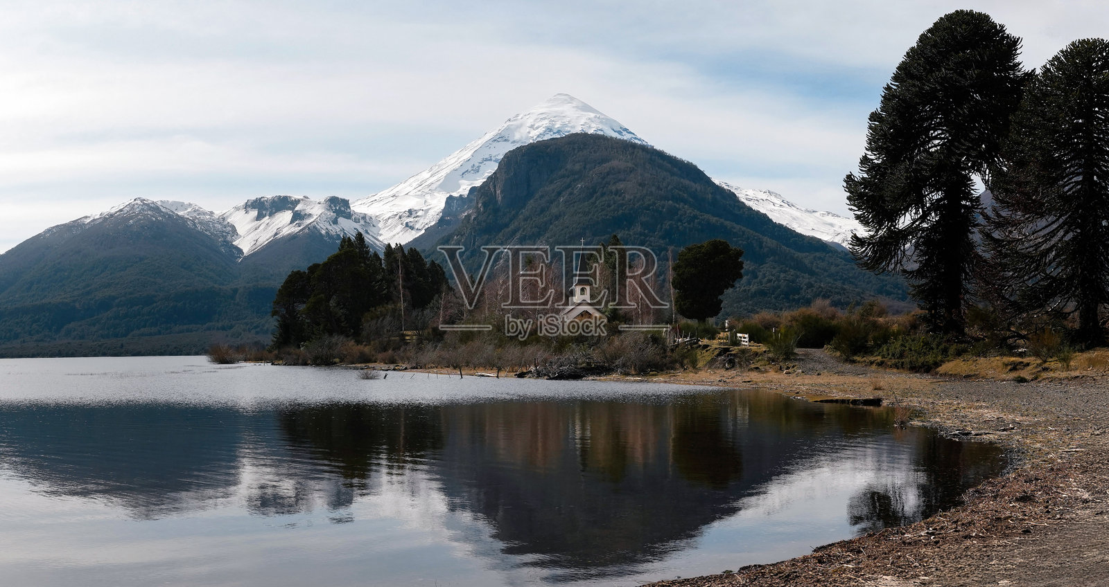 阿根廷巴塔哥尼亚，兰宁火山的雪顶倒映在湖中，旁边有一座小教堂。照片摄影图片