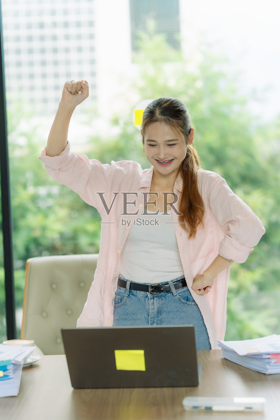 一位自由撰稿人成功完成项目后，在笔记本电脑前兴奋地举起双拳，脸上洋溢着喜悦。照片摄影图片