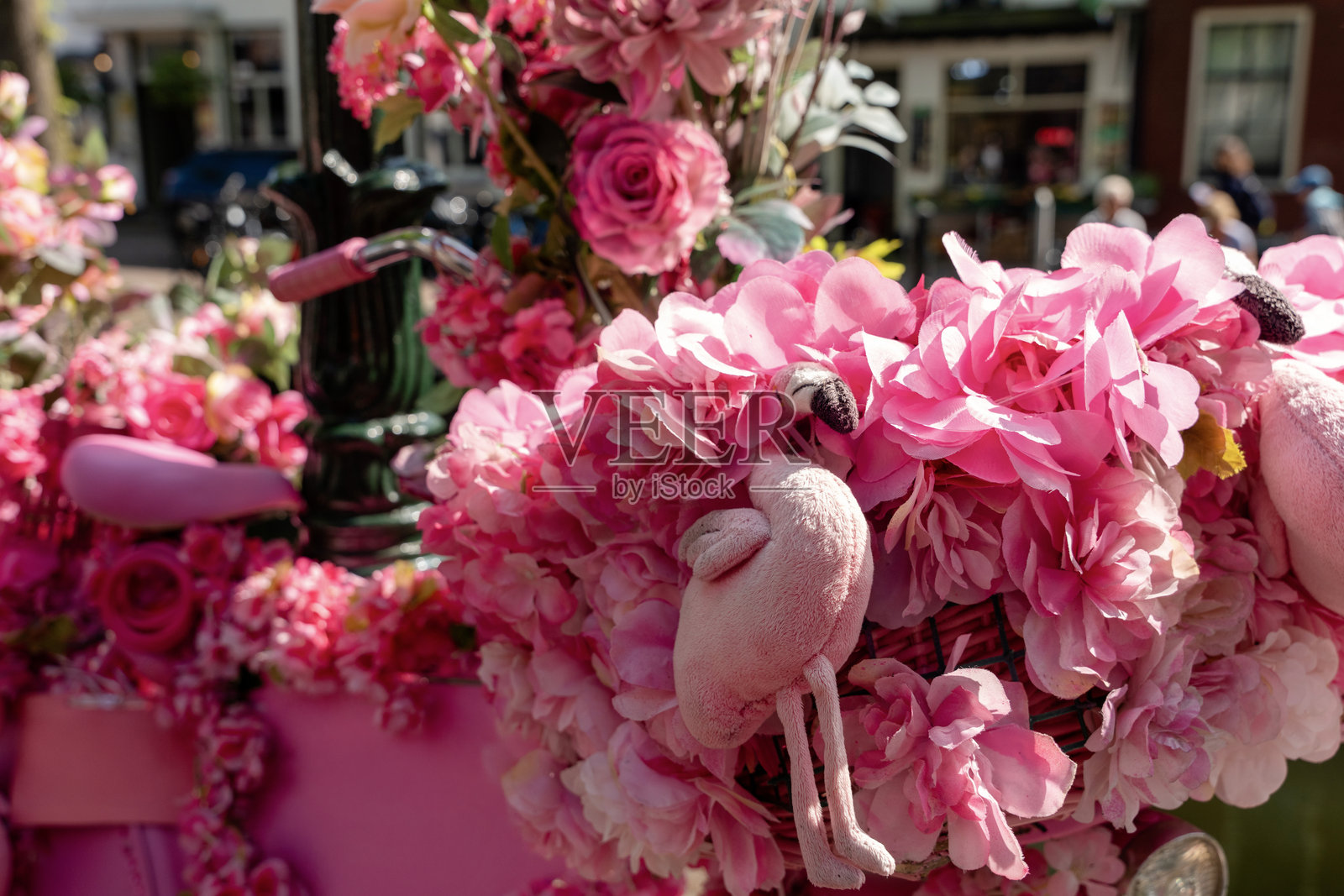 阳光明媚的日子里，生机勃勃的城市环境中，摆放着带有火烈鸟装饰的美丽粉色花艺作品。照片摄影图片