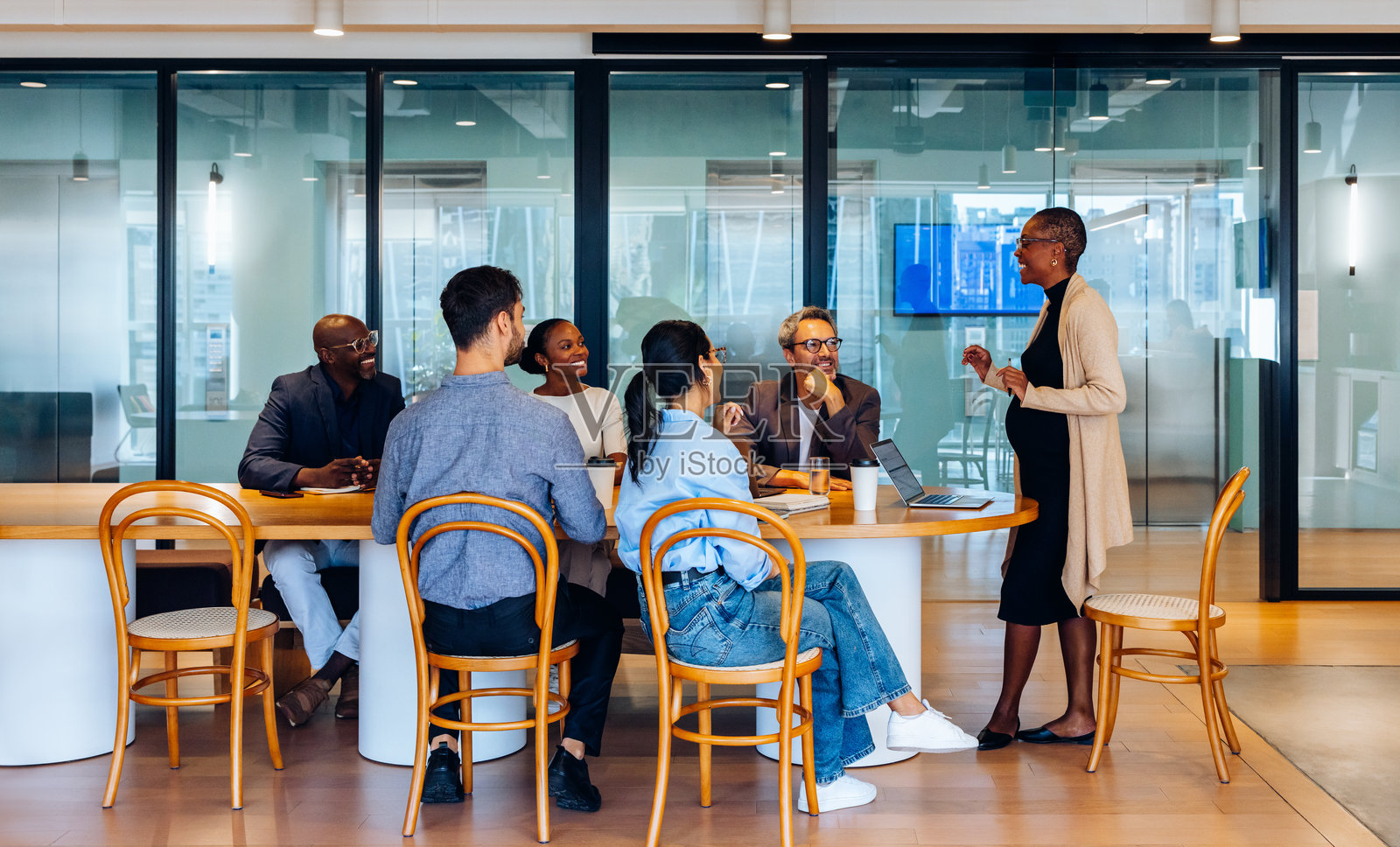 一群不同背景的专业人士围坐在共享的办公桌旁进行讨论照片摄影图片