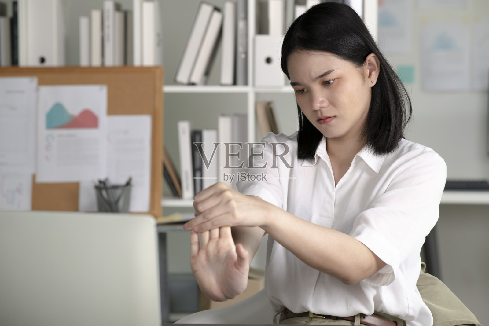 年轻的亚洲女商人长时间在电脑前工作导致手腕疼痛，正在按摩手部和手腕，健康办公室综合征概念。照片摄影图片