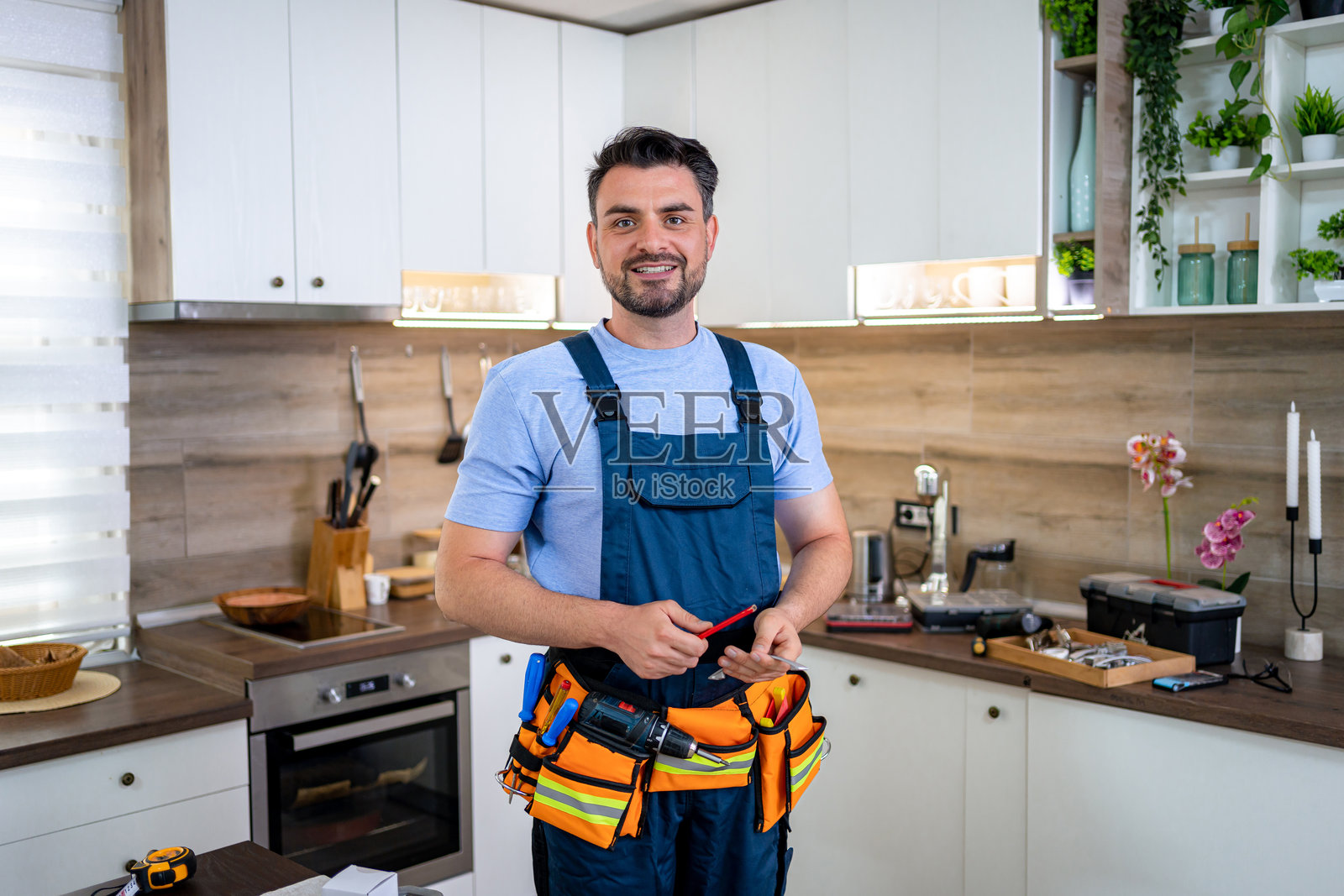 一名杂工正在现代厨房里修理东西照片摄影图片