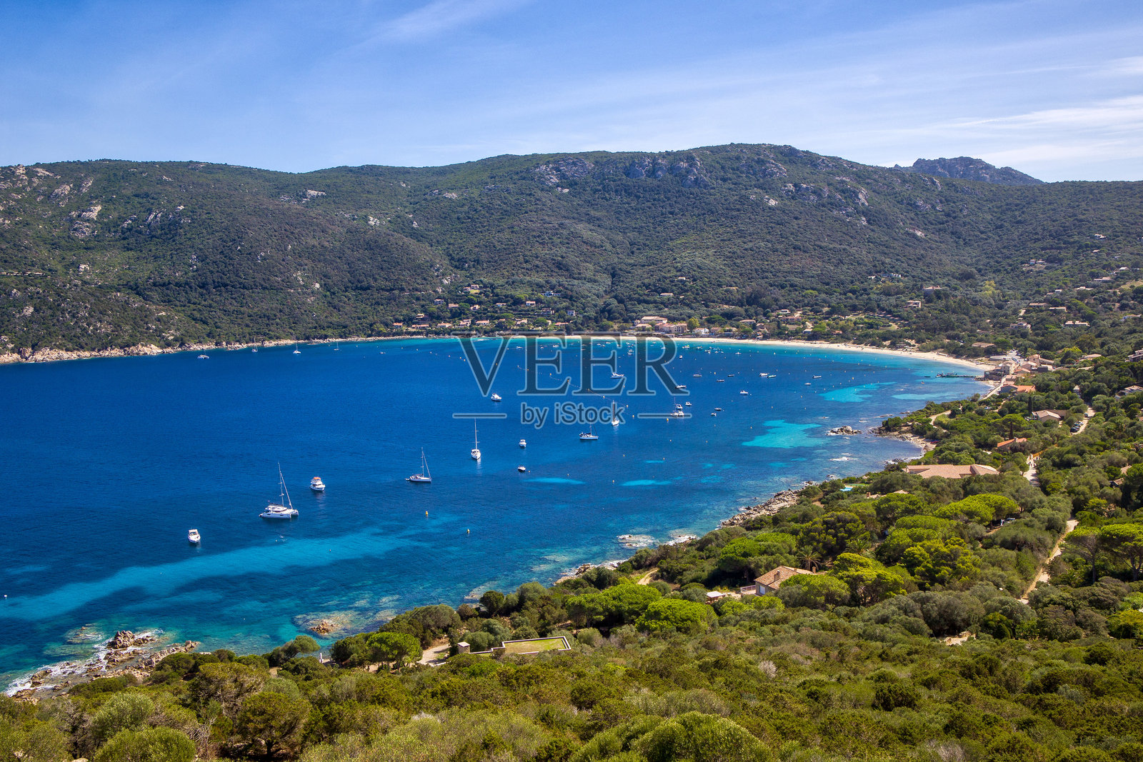 阳光明媚的蓝天下，风和日丽的科莫罗湾，几艘船停泊在清澈的蓝色和绿松石色的海水之中照片摄影图片