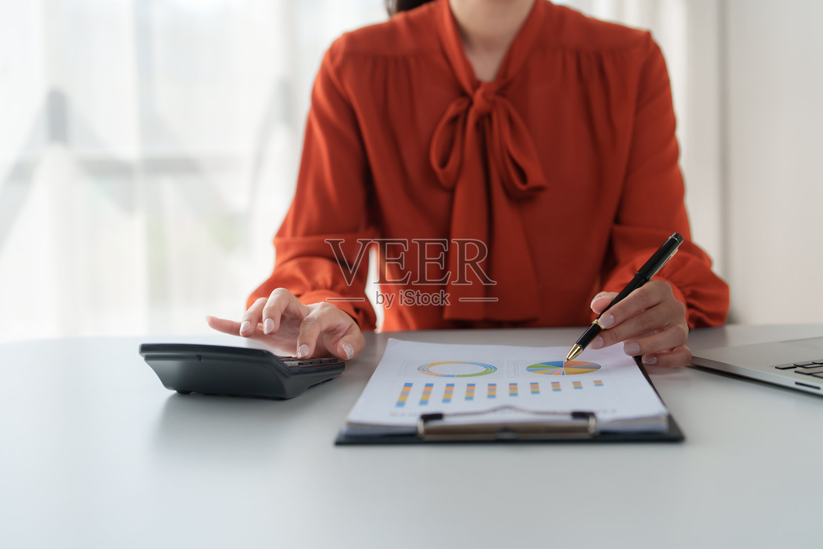 女商人在办公室分析财务图表并使用计算器照片摄影图片