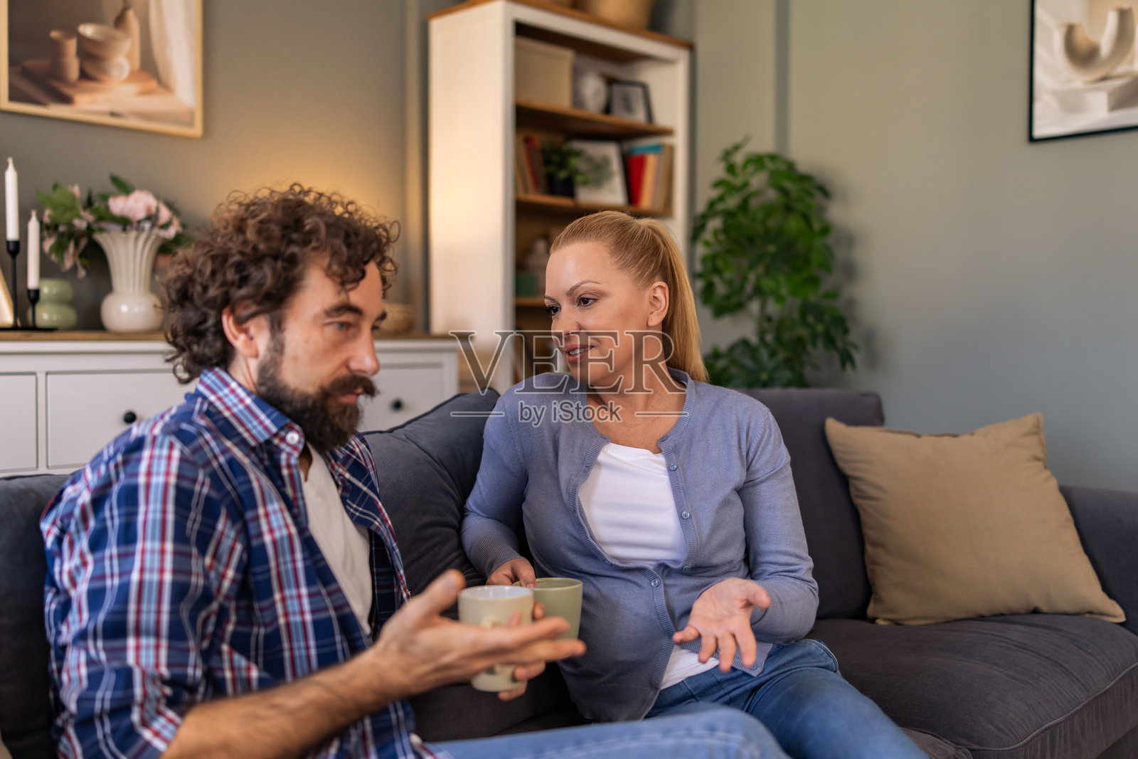 丈夫在家中坐在沙发上谈论问题，妻子认真倾听，两人坐在客厅的沙发上。照片摄影图片