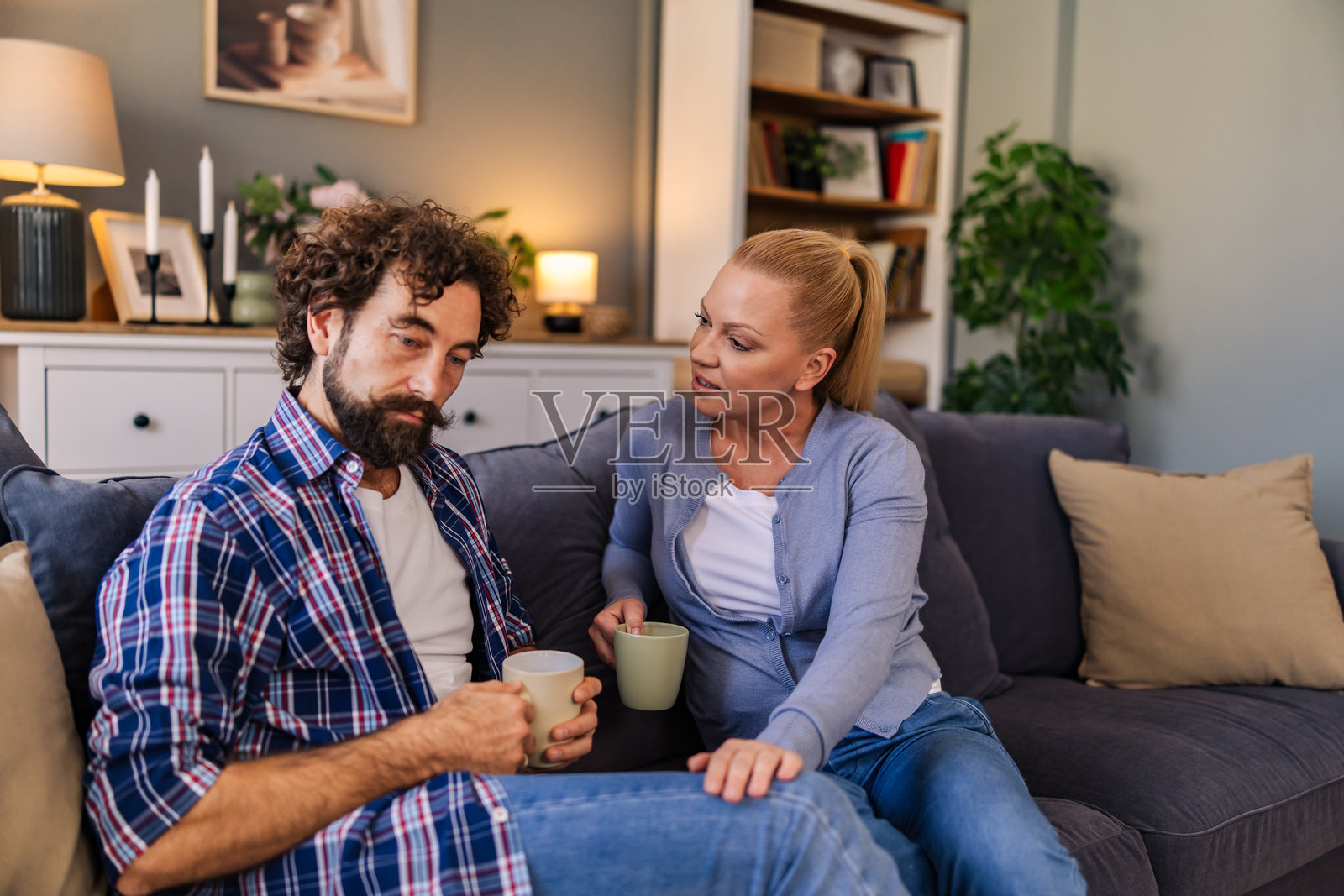 丈夫坐在家里的沙发上谈论烦恼，妻子在一旁认真倾听并给予支持，两人坐在客厅的沙发上。照片摄影图片
