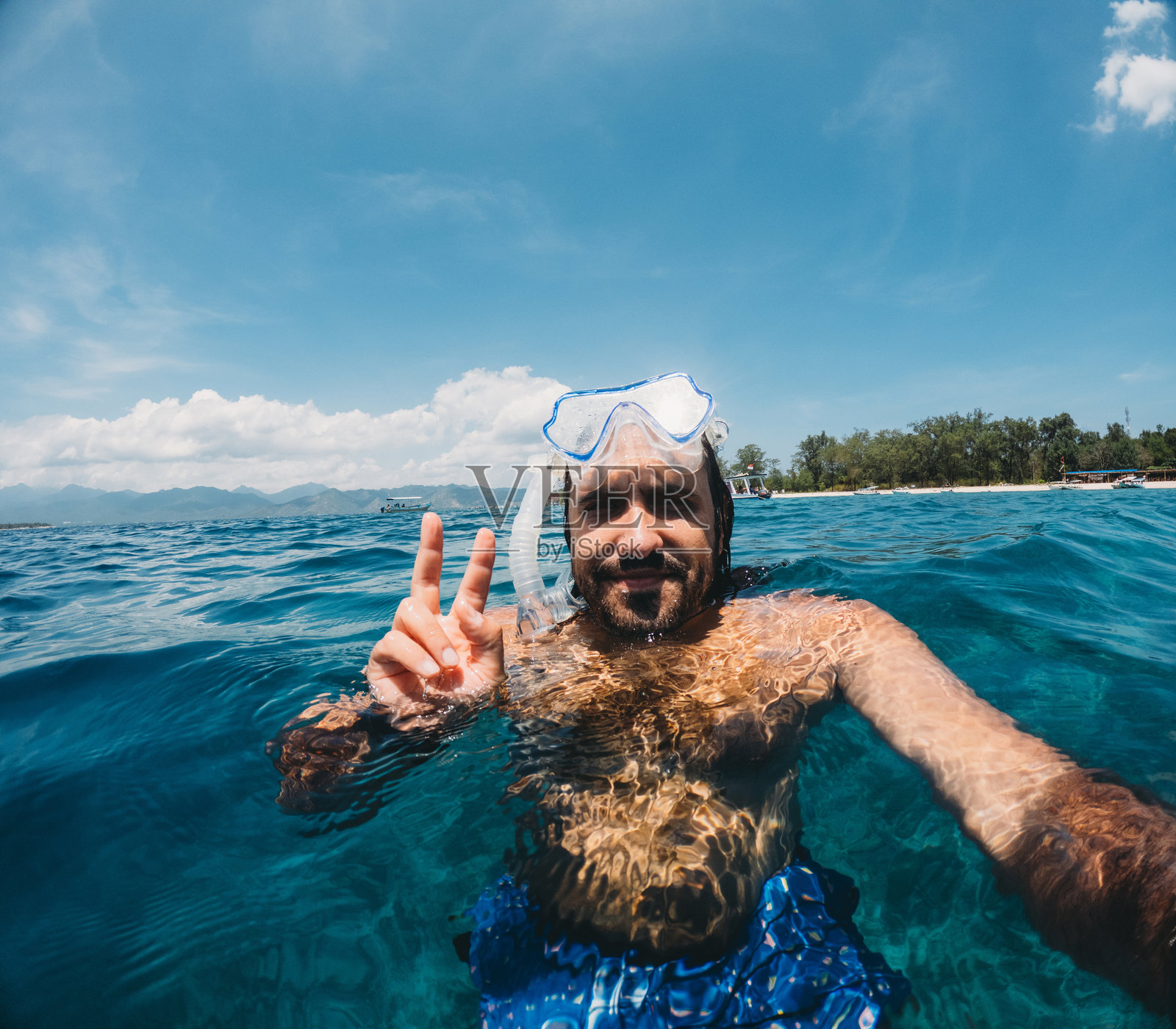 一名男子在度假时浮潜并自拍，竖起胜利手势照片摄影图片