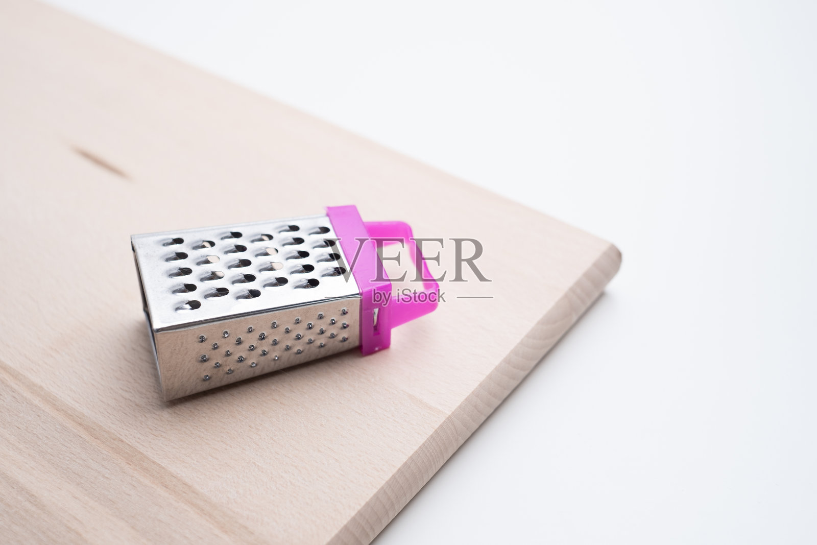 白色背景上的金属奶酪刨丝器。厨房用具。照片摄影图片