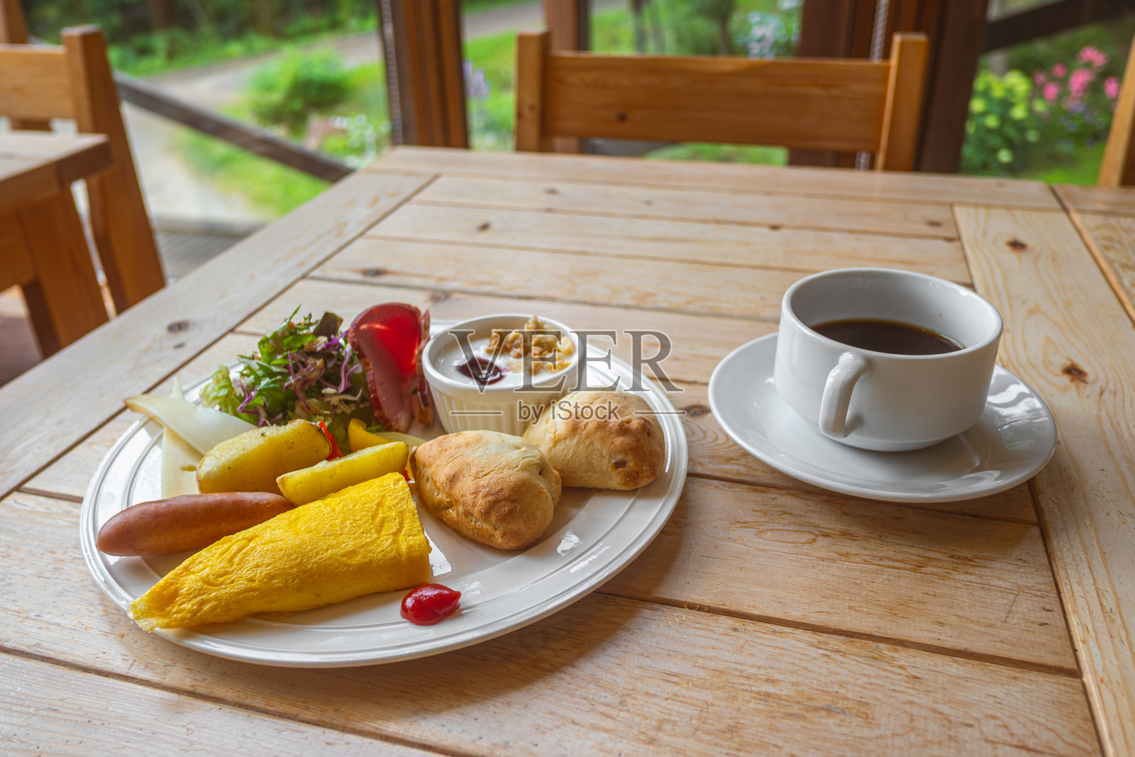 木质餐桌上的健康早餐拼盘，包含煎蛋卷、羊角面包、沙拉和咖啡。照片摄影图片