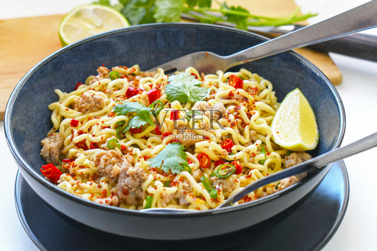 碗中装有辣椒、香菜和柠檬的辣味面条。照片摄影图片