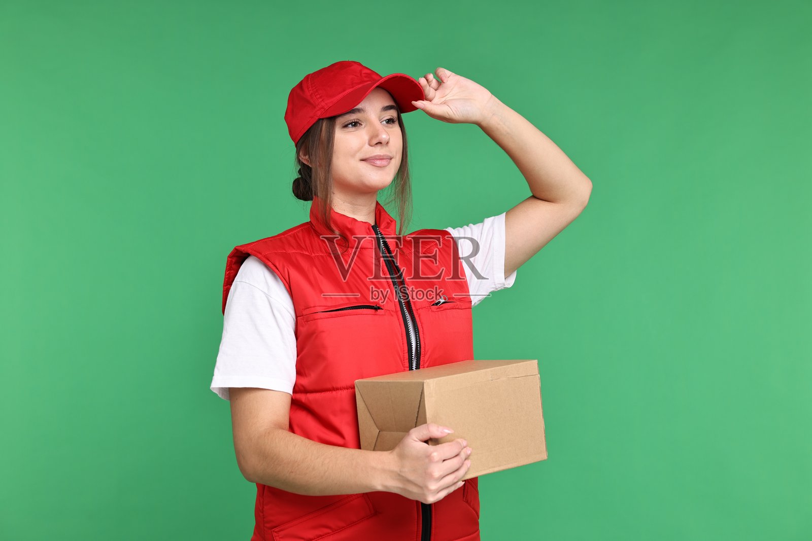 身穿制服的女孩，绿色背景上放着包裹。适合青少年的工作。照片摄影图片