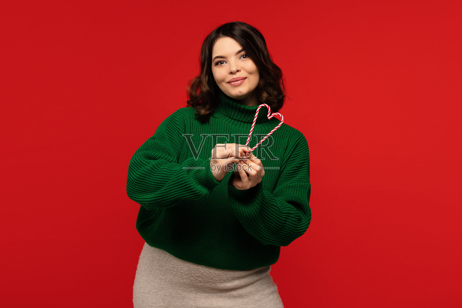 身穿绿色毛衣的女子手持心形拐杖糖照片摄影图片