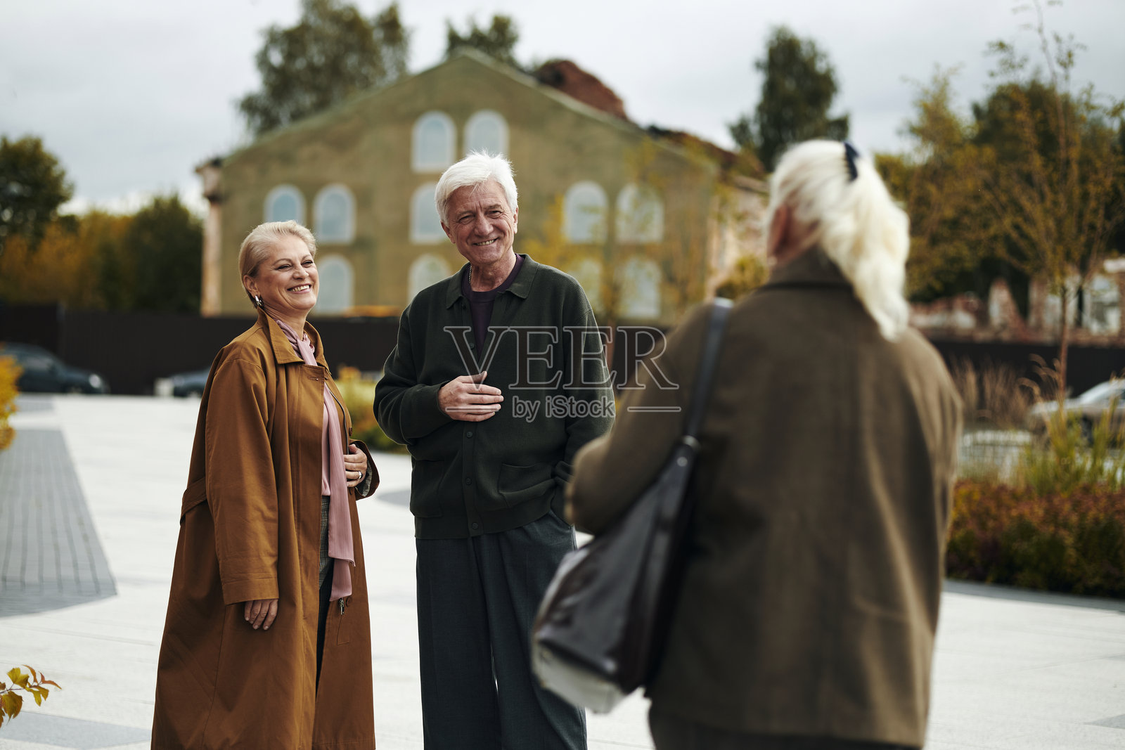 一对年长的夫妇在户外微笑着向中年女性朋友打招呼照片摄影图片
