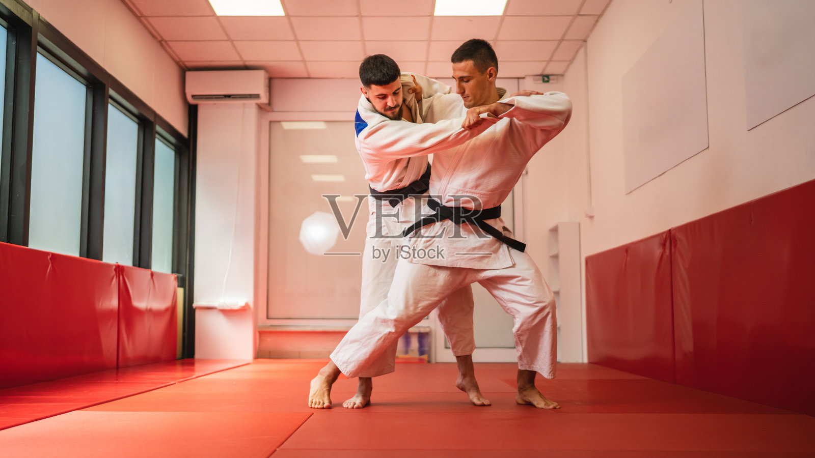 柔道训练道场里，两位男士正在进行摔跤训练照片摄影图片