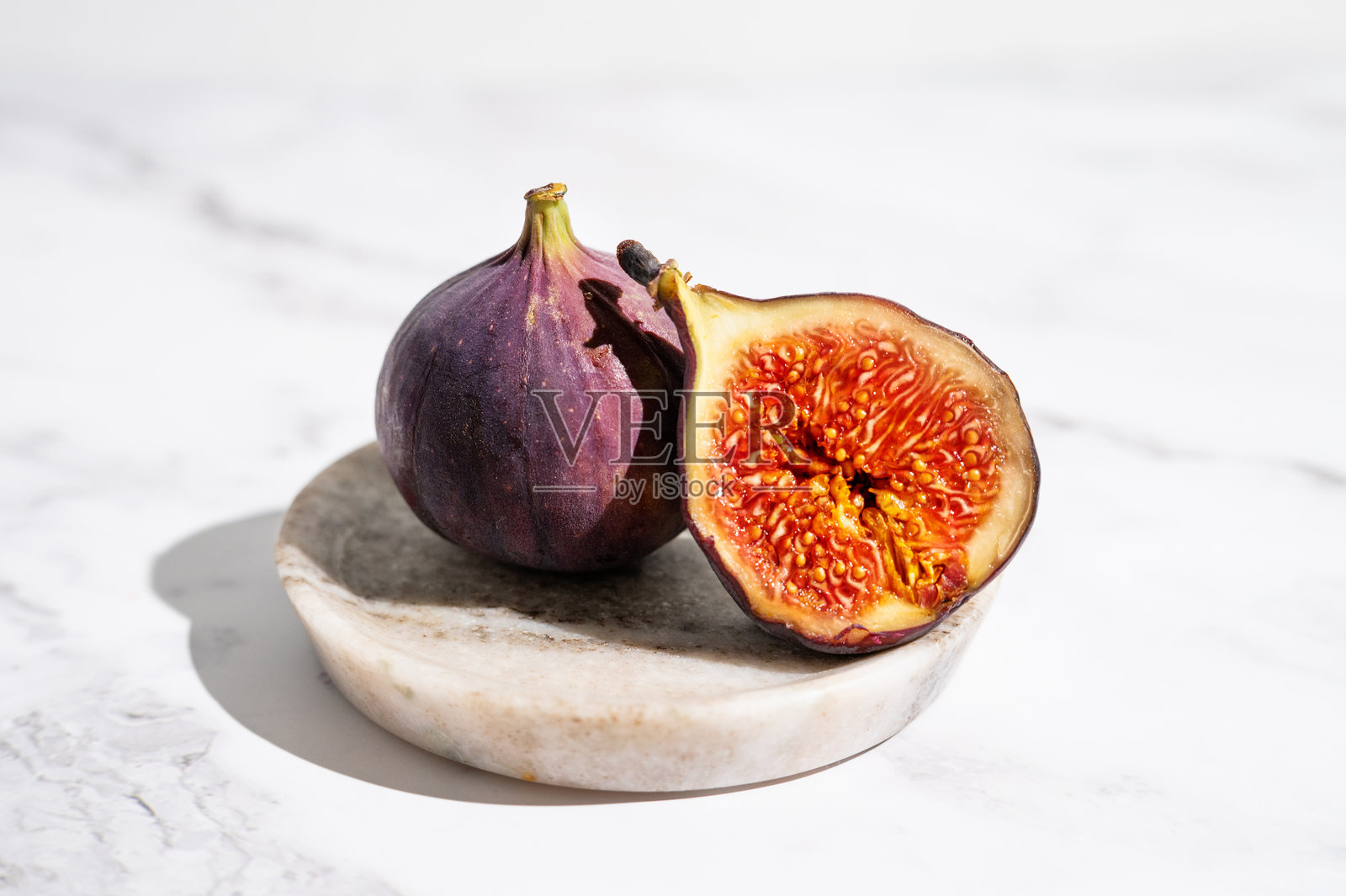 盘子里的新鲜无花果，深紫色的果皮和鲜红的果肉。照片摄影图片