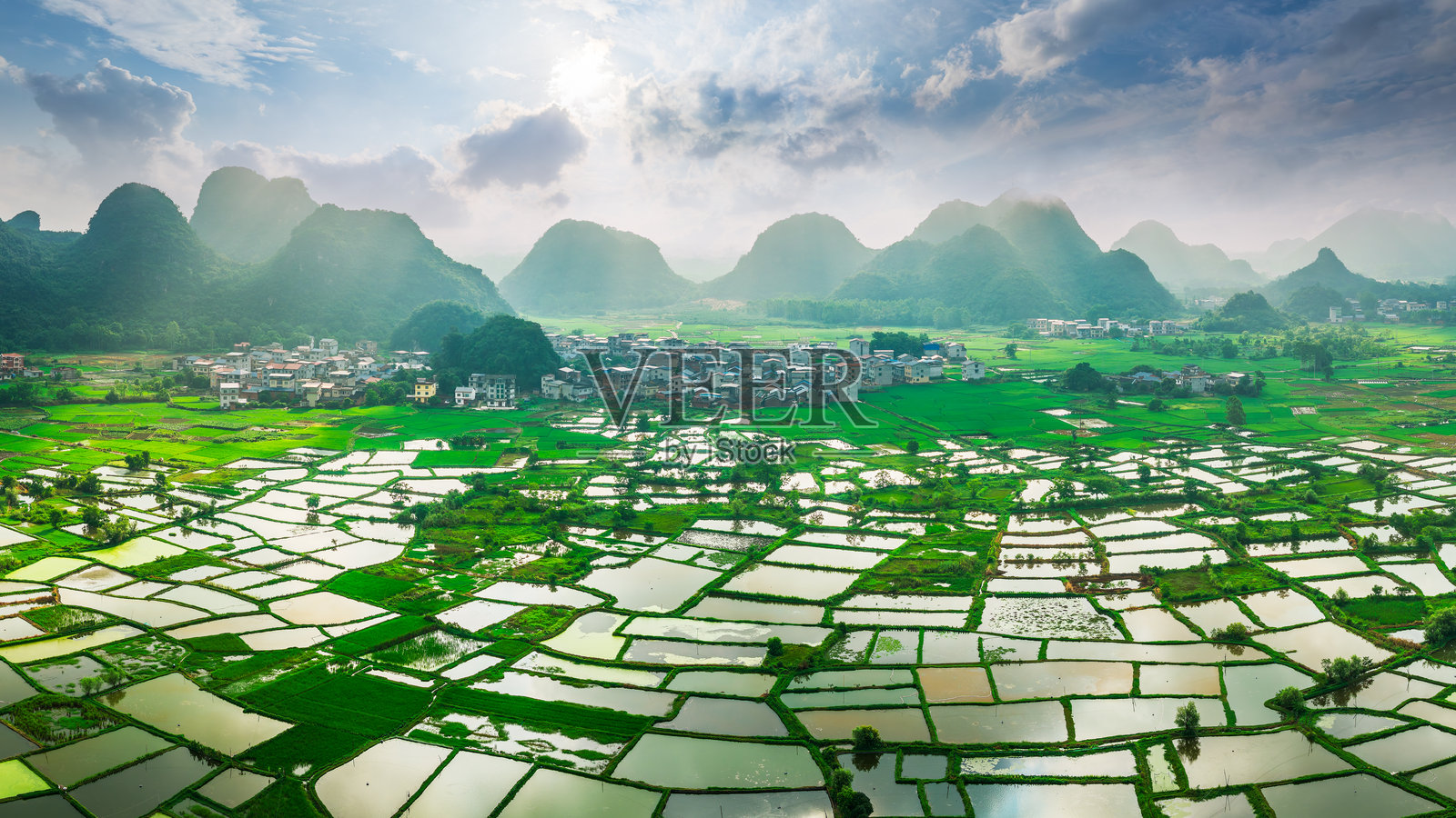 阳光穿透喀斯特山脉，照耀着坐落其中的乡村村落和稻田，景色令人叹为观止。照片摄影图片