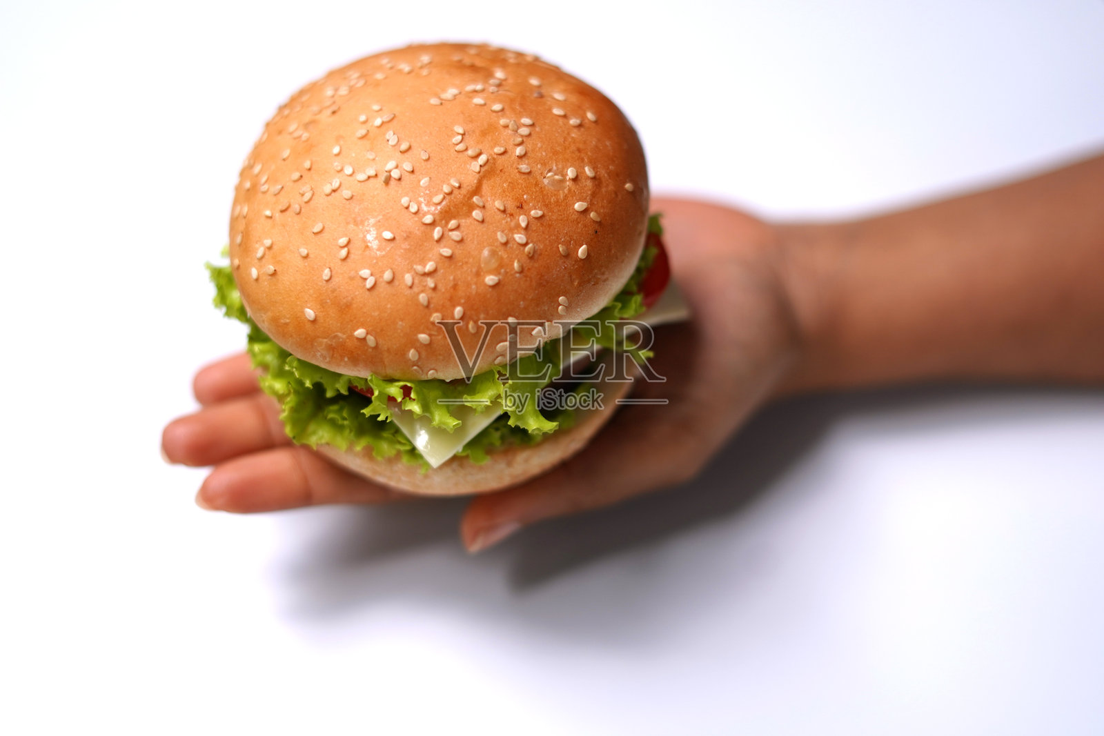 一只手拿着美味的汉堡。白色背景。照片摄影图片