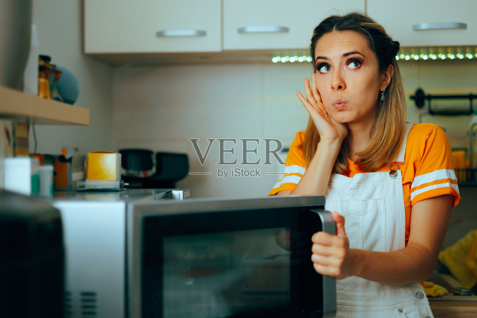 惊讶的家庭主妇正在打开微波炉的门照片摄影图片