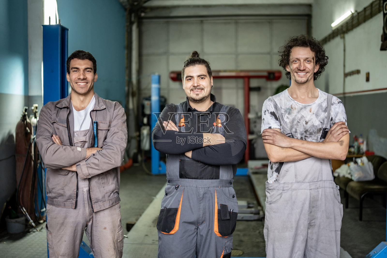 三名技艺娴熟的汽车技师自信地站在车间里，随时准备处理项目照片摄影图片