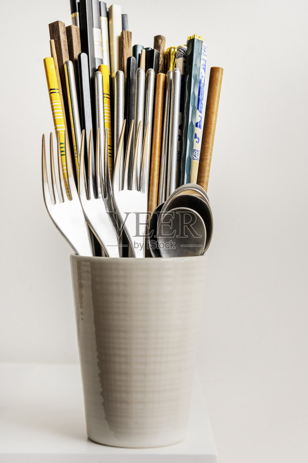 一个瓷碗，配有金属叉子和勺子，以及一堆各种用于进食的筷子照片摄影图片