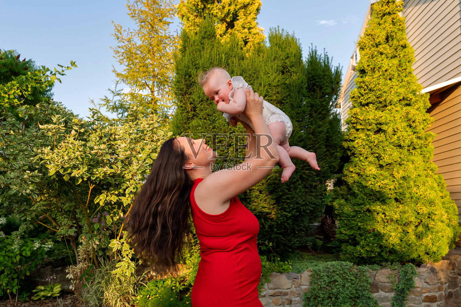 妈妈抱起—在傍晚的天空下微笑照片摄影图片