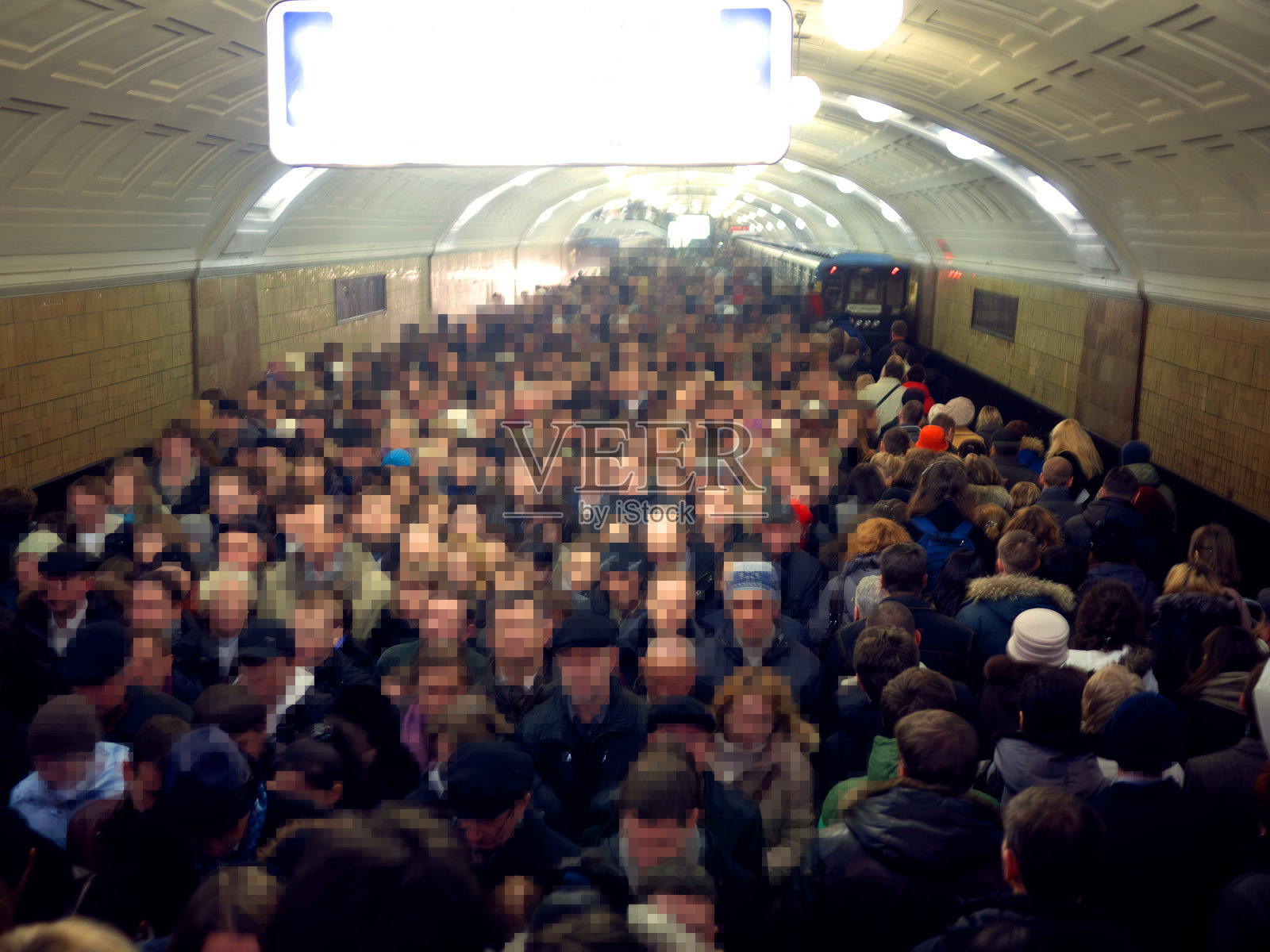 在莫斯科地铁站的上下班高峰时段，站台上挤满了人群，他们的人脸已被像素化处理。照片摄影图片