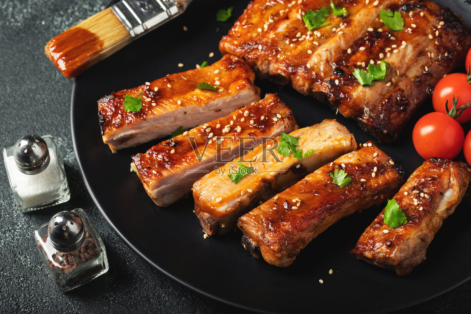 夏日烧烤烤制的美味烤猪肋排，盛放在盘中，淋有酱汁。俯视角度，有空白空间可供添加文字。照片摄影图片