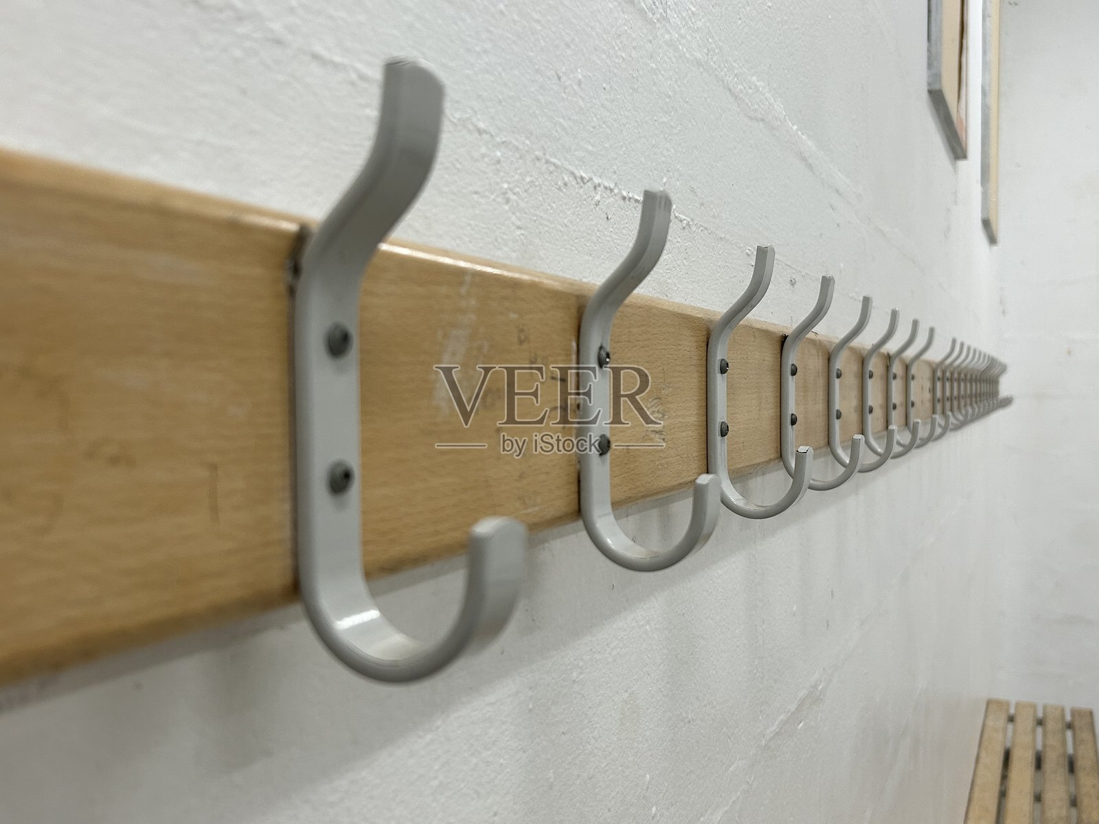 走廊里挂在木质背板上的一排银色金属衣帽钩照片摄影图片