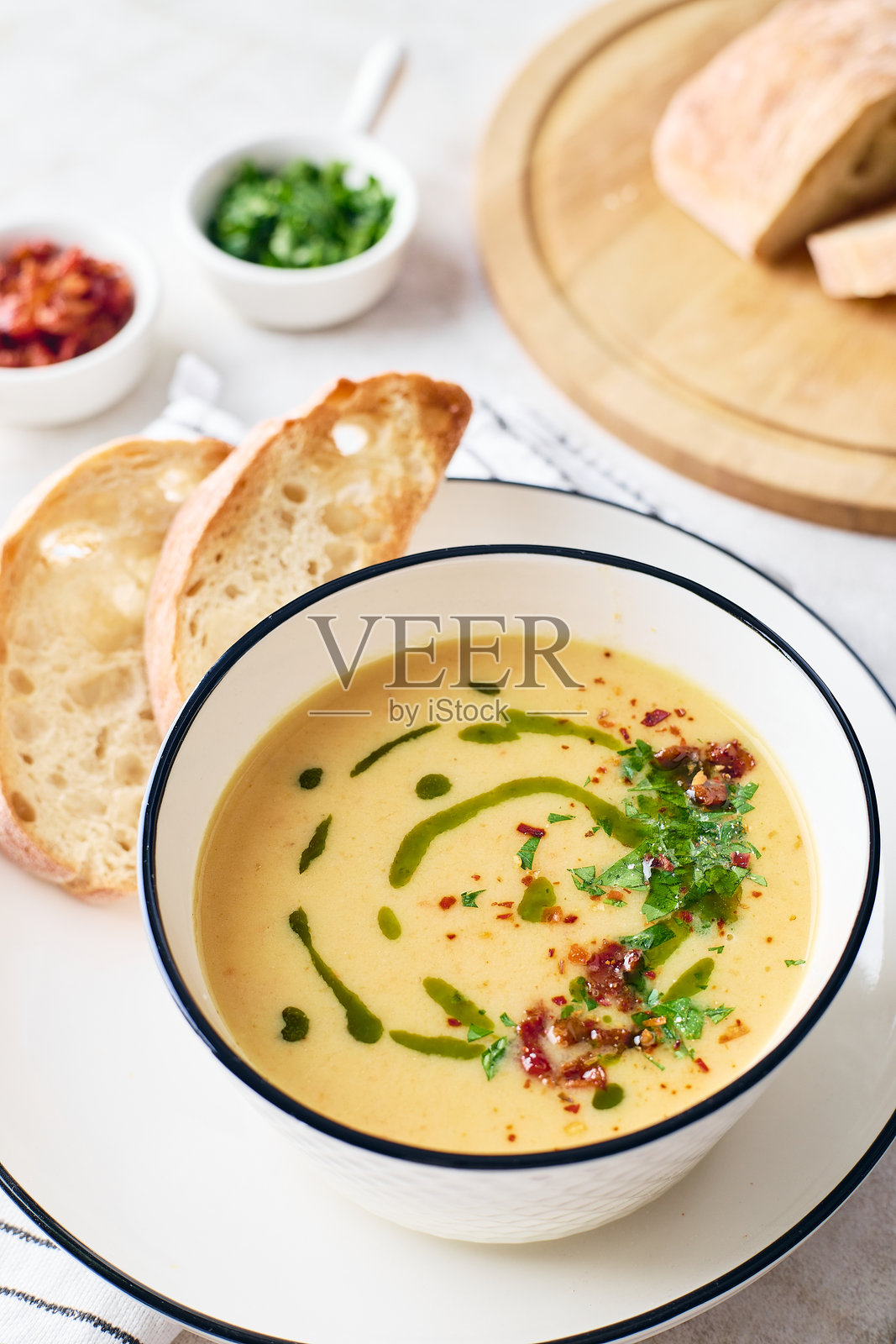 白色碗中盛有土豆汤，配以欧芹、培根和烤面包丁，这是一道暖心餐点。照片摄影图片