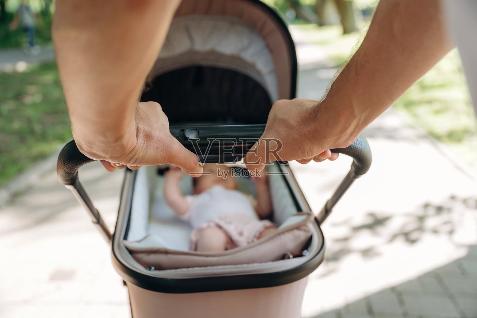 第一人称视角，男人抱着婴儿摇篮，在公园里照片摄影图片